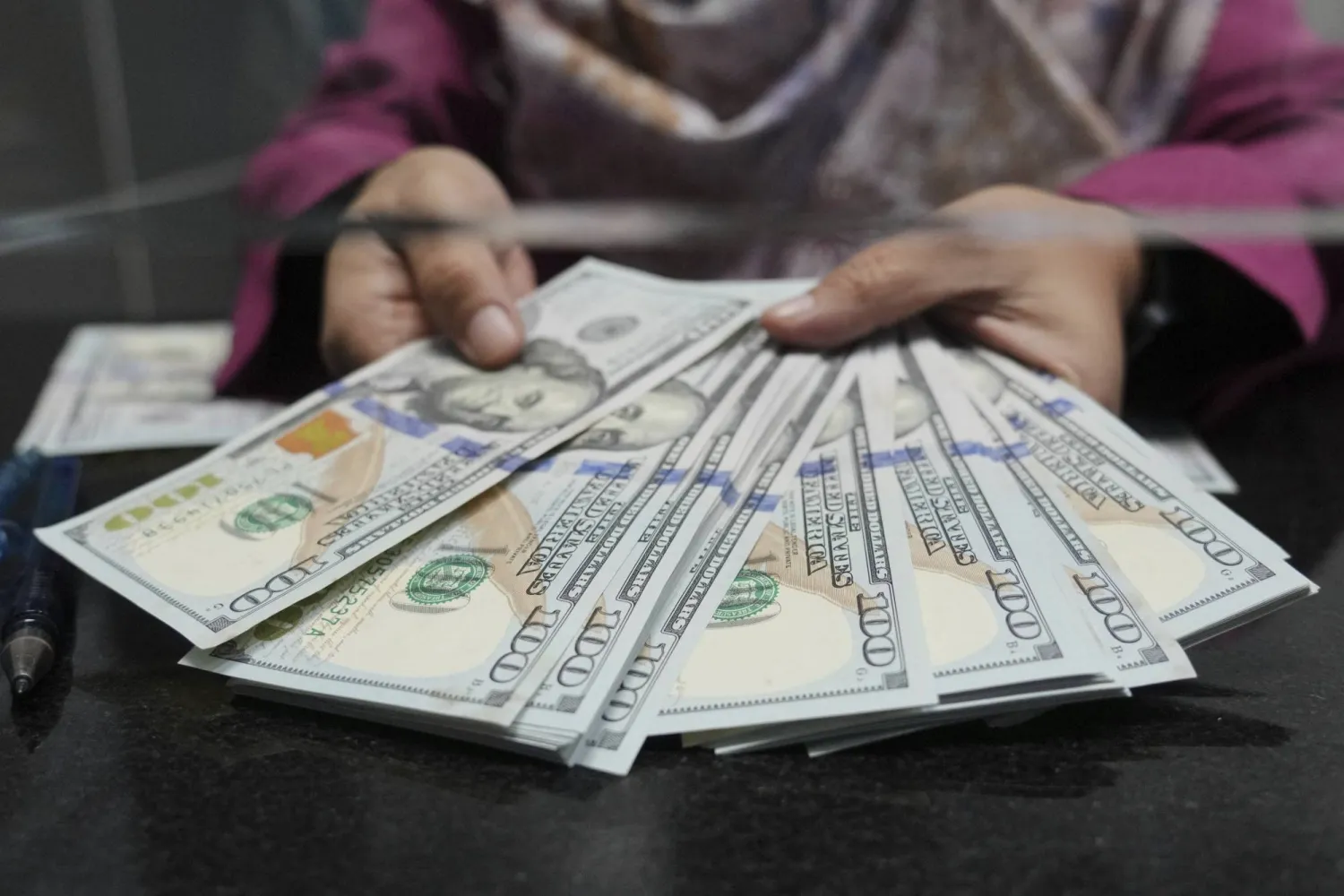 أوراق من الدولار الأميركي لدى محل صرافة (أ.ب)