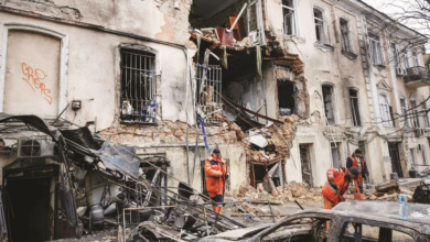 عمال نظافة في موقع مبنى سكني تعرض لغارة روسية (رويترز)